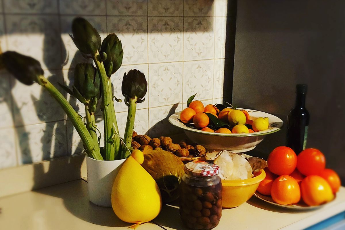αγκινάρες, βάζο με ελιές, ντομάτες, φρούτα σε πάγκο κουζίνας