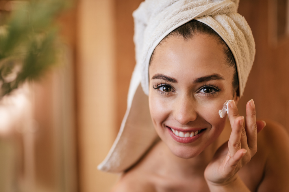 woman with towel on head uses hydrating face cream