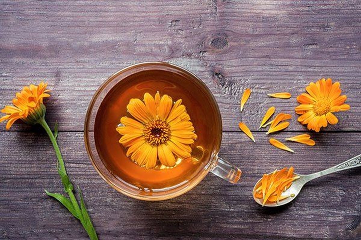 τσάι καλέντουλας σε διάφανο ποτήρι με λουλούδι στην επιφάνεια