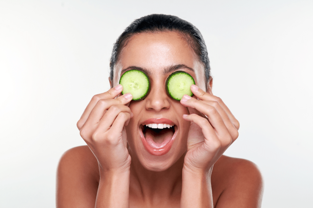 woman puts cccumber slices on her eyes