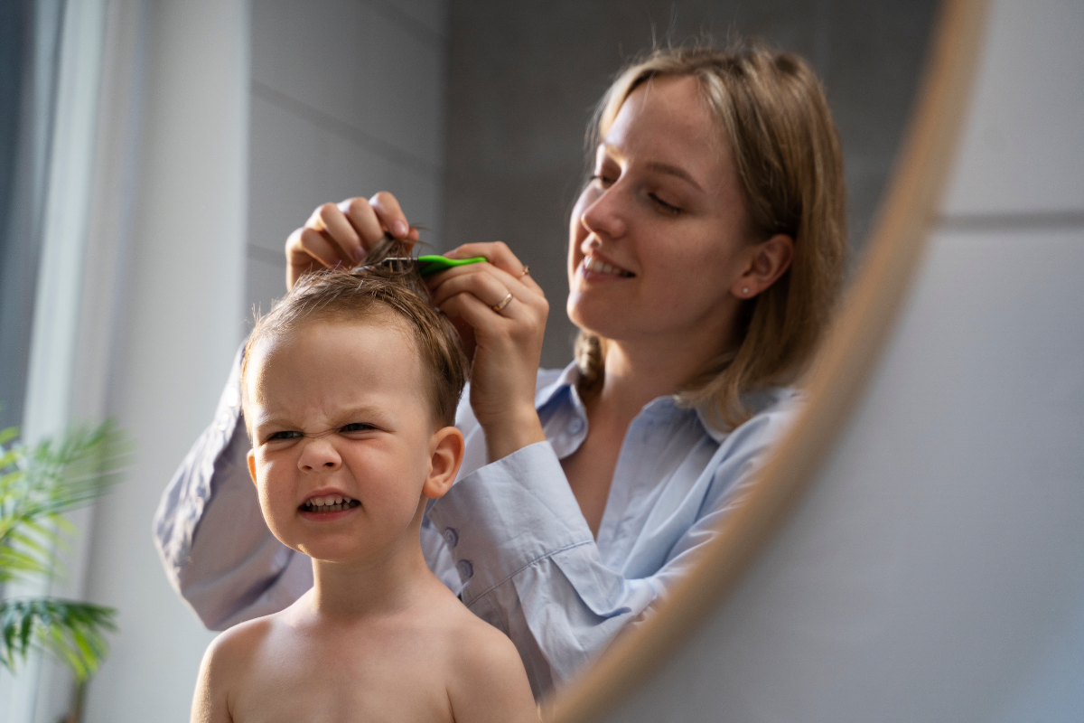 mother looks for lice on boys head in front of mirror