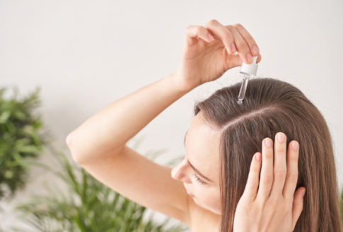woman puts castor oil on hair