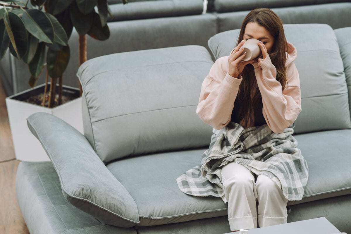 Sick woman sitting at home with warm clothes.