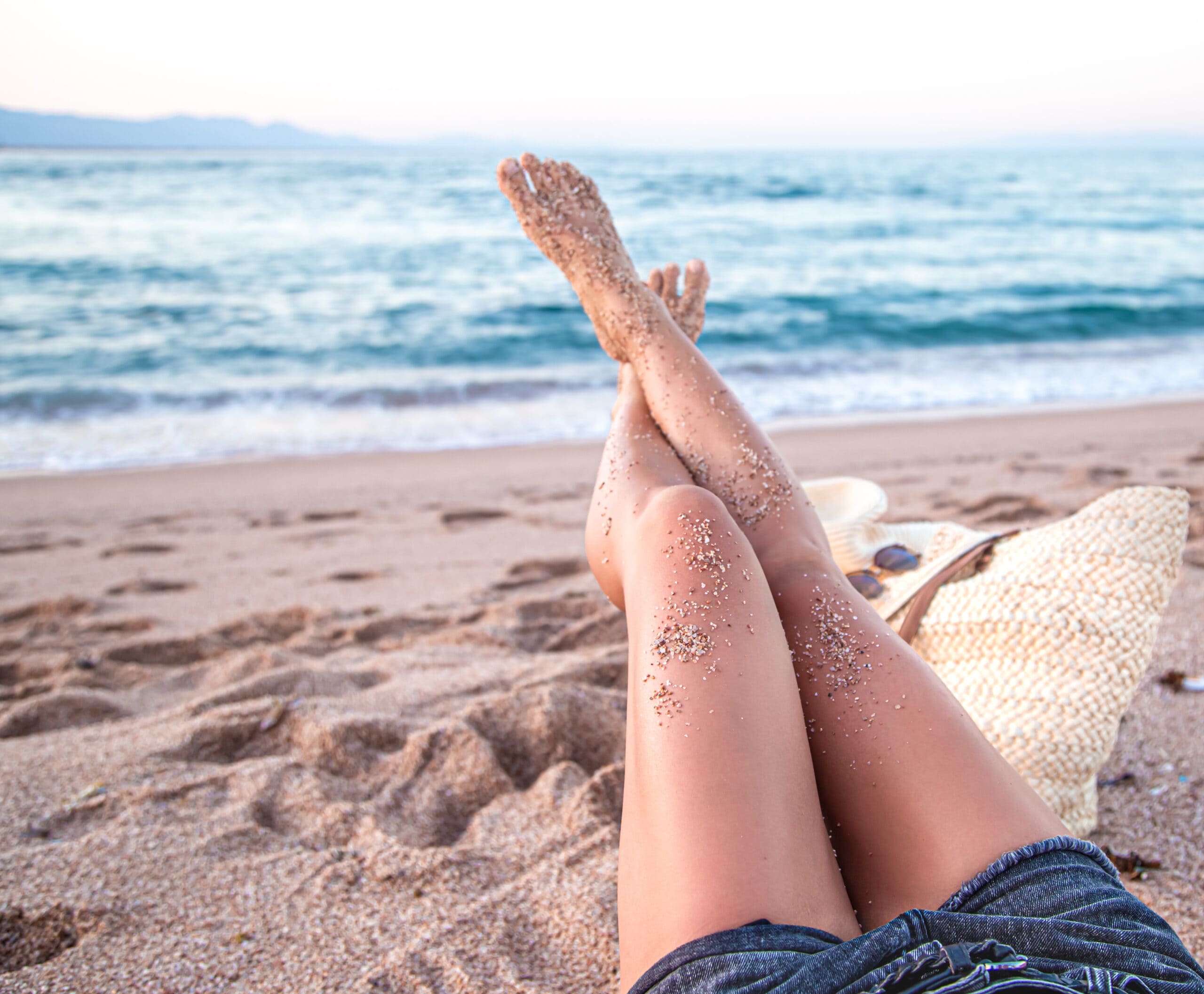 Γυναικεία πόδια στην άμμο σε παραλία.