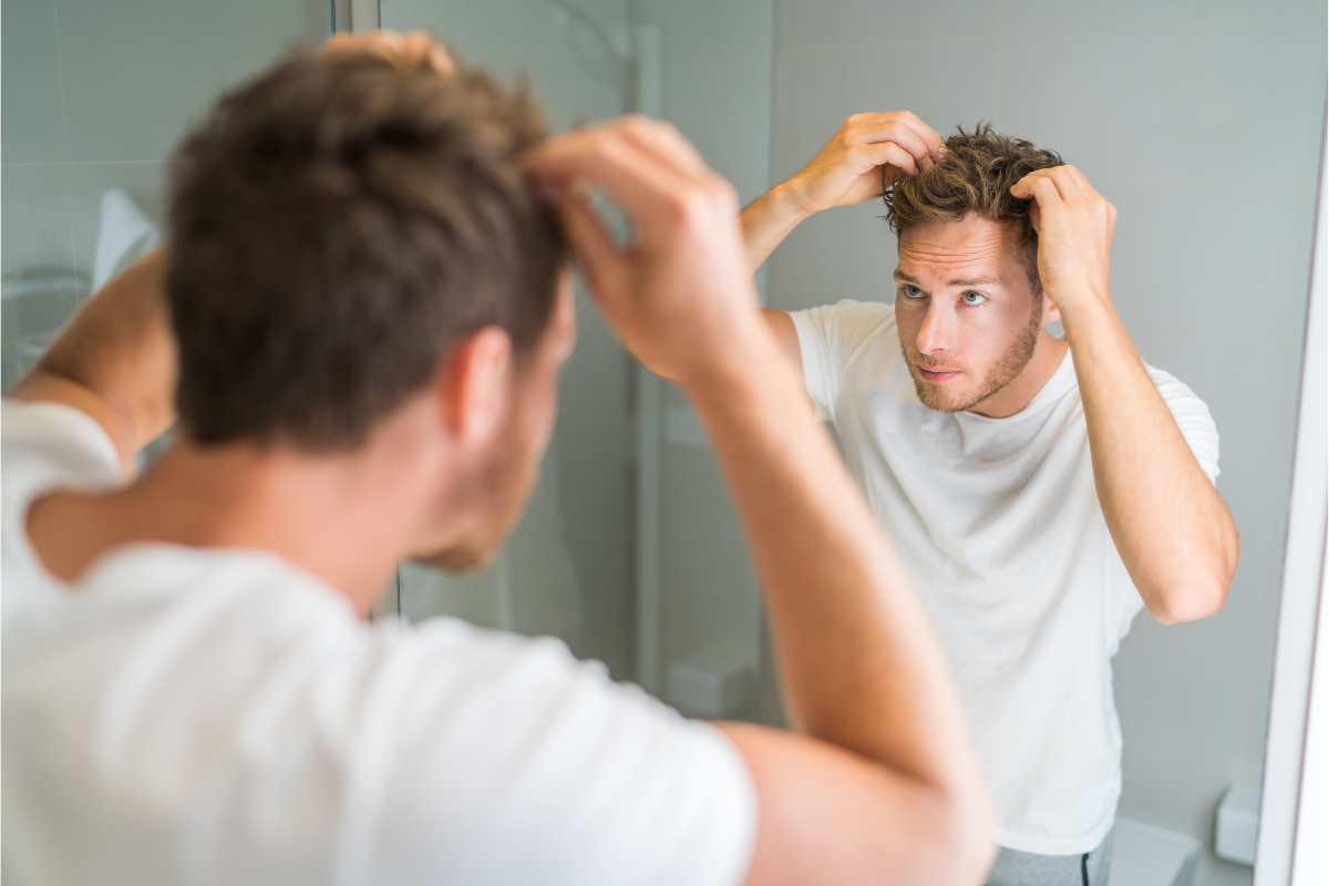 νεαρός άνδρας κοιτάζει στον καθρέφτη τα μαλλιά του