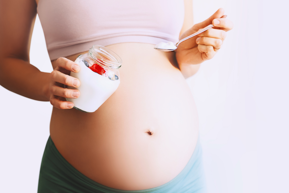 pregnant holds a jar with yogurt and berries