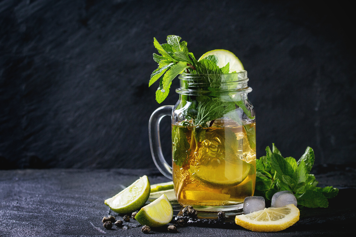 πράσινο τσάι κρύο με φύλλα μέντας, φέτες λεμόνι και λάιμ