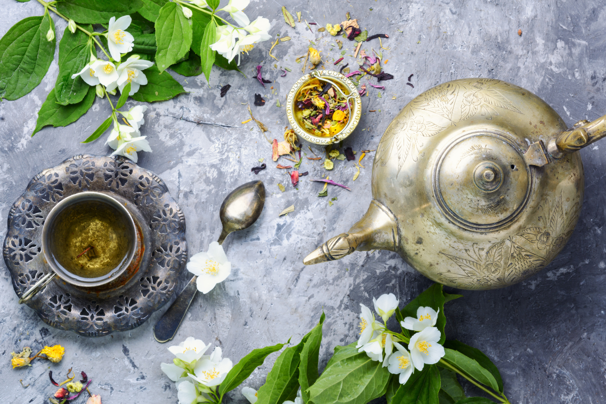 τσαγιέρα και φλιτζάνι με τσάι ανάμεσα σε λουλούδια