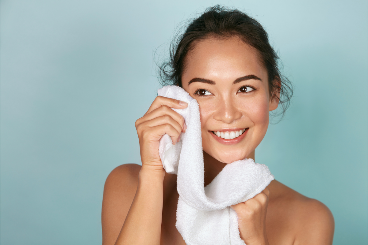 woman wipes her face with white towel