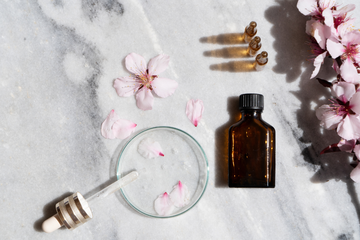 almond oil in little bottle next to small glass plate and flowers