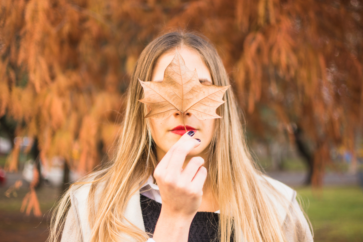 woman hold a dry leaf in front of her face