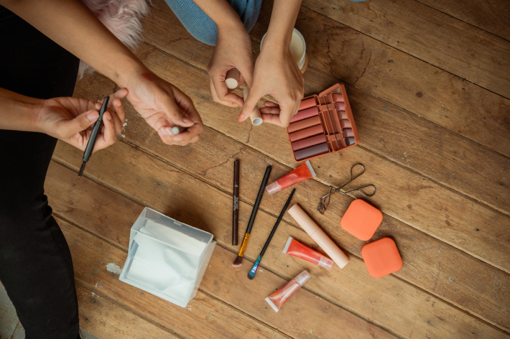κοπέλες διαλέγουν μολύβι ματιών με είδη μακιγιάζ στο πάτωμα
