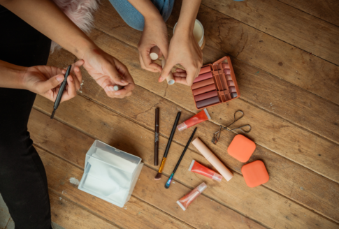 κοπέλες διαλέγουν μολύβι ματιών με είδη μακιγιάζ στο πάτωμα