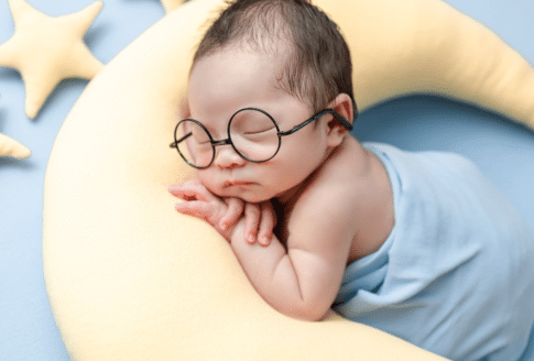 νεογέννητο με γυαλάκια κοιμάται πάνω σε μαξιλάρι-φεγγαράκι